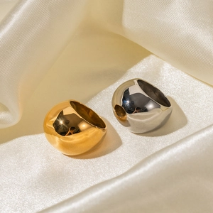 Polished 18K gold and silver chunky dome rings on a beige silk background