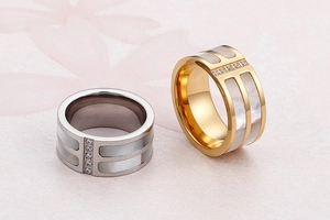 Detail of wide band ring featuring white shell inlay and zircons in gold and silver