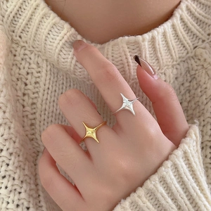 Close-up of gold and silver starburst rings stacked on model against knit background