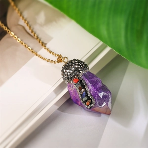 Macro detail of iridescent purple crystal pendant with multicolored rhinestones on gold chain