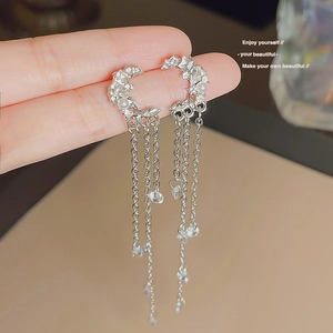 Close-up of crescent moon stud earrings with silver tassels and sparkling cubic zirconia
