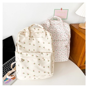 Detail view of two floral canvas backpacks on a desk with a laptop and vintage lamp