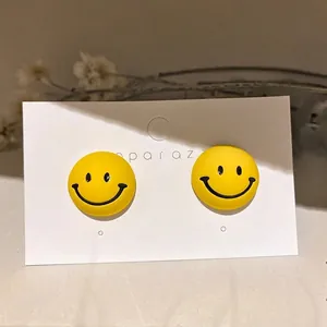 Fashionable yellow smiley face stud earrings with matte finish on jewelry display card