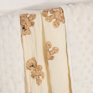 Close-up of double-sided baby blanket featuring minky dot fabric and bear muslin gauze