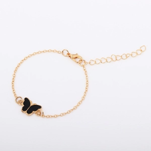 Detail of adjustable gold chain bracelet featuring a black butterfly charm and lobster clasp