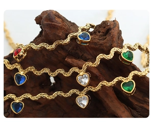 Macro shot of gold plated wave chain with colorful heart zirconia stones on wood