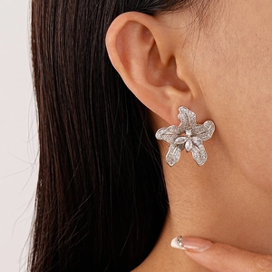 Close-up of a silver flower stud earring with sparkling zircons worn by a model