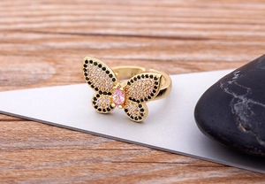 Macro detail of 18K gold-plated butterfly ring with pink and black cubic zirconia stones