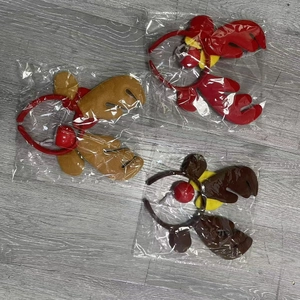 Three plush reindeer antler headbands with bells in clear packaging on a wooden floor