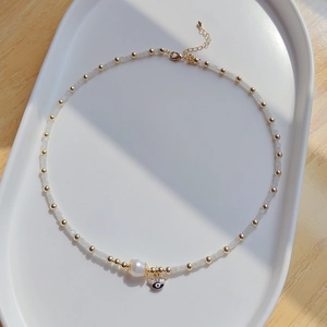Collier de perles d'eau douce avec pendentif œil bleu et perles dorées sur plateau
