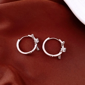 Detail of silver hoop earrings with zircon knot design on dark red velvet fabric