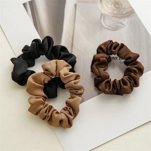 Gros plan de chouchous en satin noir, kaki et marron avec une texture soyeuse brillante