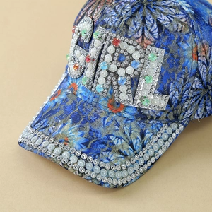 Detailed view of floral lace baseball cap with GIRL crystal letters and pearl brim