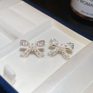 Gros plan de boucles d'oreilles nœud en zircon étincelant dans une boîte à bijoux de luxe
