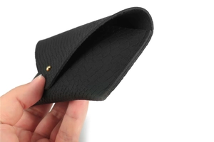 Close-up of black snakeskin texture faux leather sunglasses pouch with gold snap button