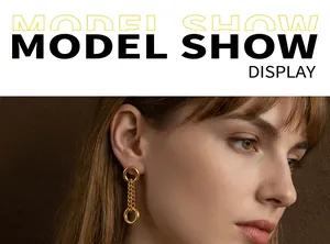 Close-up of model wearing gold hoop and chain dangle earrings in a minimalist style