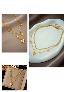 Détail du collier double rang doré avec pendentif cœur et perles carrées sur du velours
