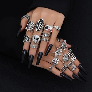 Detail of gothic silver ring set featuring skull and spider designs on black nails