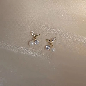 Close-up of cherry pearl earrings in gold finish with sparkling crystal details