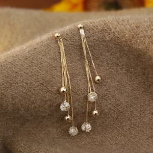 Elegant long gold tassel earrings with clear crystal spheres on brown velvet fabric