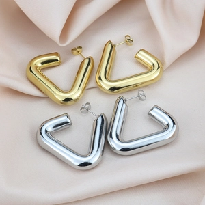 Polished triangle hoop earrings in gold and silver finish on pink silk fabric