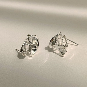Macro detail of silver knot heart stud earrings with polished metallic luster finish