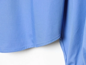 Détail de l'ourlet et de la texture en popeline d'une chemise bleue à manches ballon