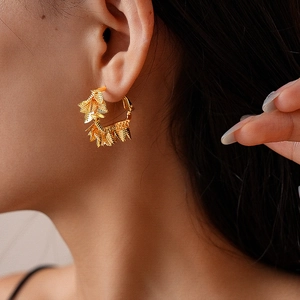 Détail de créoles géométriques plaquées or 18 carats avec petits pendentifs feuilles sur mannequin