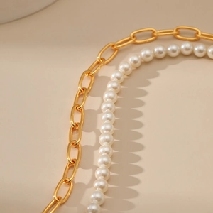 Macro shot of elegant shell pearls combined with gold paperclip chain link textures