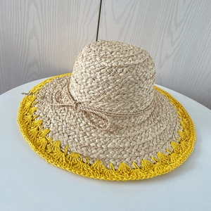 Détail du chapeau en raphia à larges bords avec bordure jaune et nœud tressé