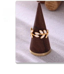 Detail of 18k gold plated leaf ring with white enamel on a wooden display stand