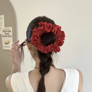 Detail view of large burgundy satin scrunchie styled in hair with elegant silk pleats
