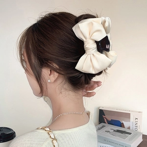 Elegant beige satin bow hair claw clip for girls worn by a model in a cozy home setting