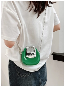 Glossy green mini chain bag with silver handle worn by model on shoulder