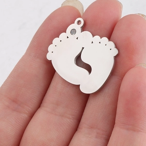 Close-up of a silver baby feet pendant in polished stainless steel with a clear rhinestone