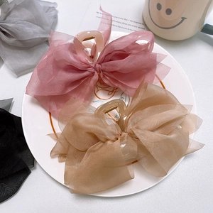 Close-up of pink and beige tulle bow hair claws on a white plate with soft lighting