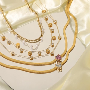 Gold layered necklace with pearls shells zircons and heart charms on a satin background