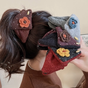 Detailed close-up of knitted floral hair claw clips with elegant golden metal buckles