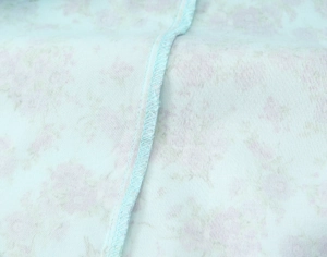 Macro detail of overlock stitching on light blue floral poplin dress fabric