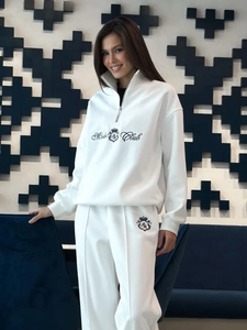 Detail shot of the Moda Club crown emblem embroidery on white fleece sweatshirt