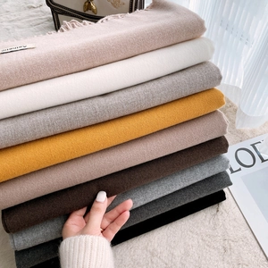 Stack of colorful cashmere-feel scarves with fringe edges in neutral and earthy tones