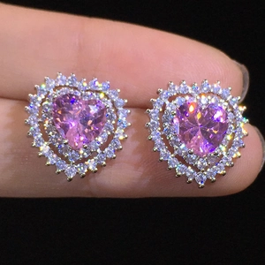Sparkling pink heart stud earrings with cubic zirconia halo in a hand-held close-up view