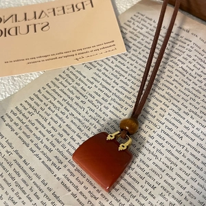 Detailed macro of red-brown faux leather bag pendant with gold buckle and wooden bead