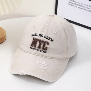 Detail view of beige cotton baseball cap featuring NYC embroidery and distressed finish