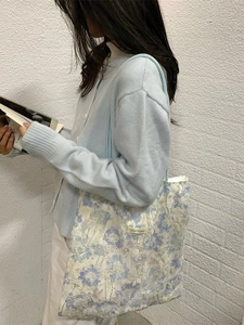 Floral embroidery lace tote bag with blue flowers shown on model shoulder for travel