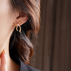 Gros plan d'une boucle d'oreille nœud doré portée par un mannequin avec un fond bokeh élégant