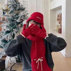 Detail of red knit scarf, hat and gloves set with white bows in a festive setting