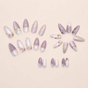 Detail of purple almond press-on nails with pearl, bow, and floral art designs
