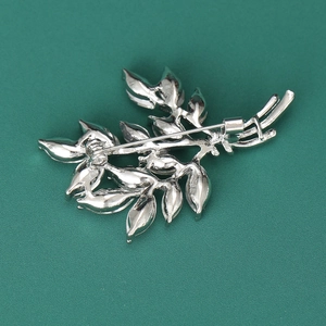 Silver leaf wheat brooch with crystal details shown on a dark green background