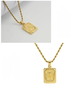 Macro detail of gold square pendant necklace with letter A engraving and twist chain